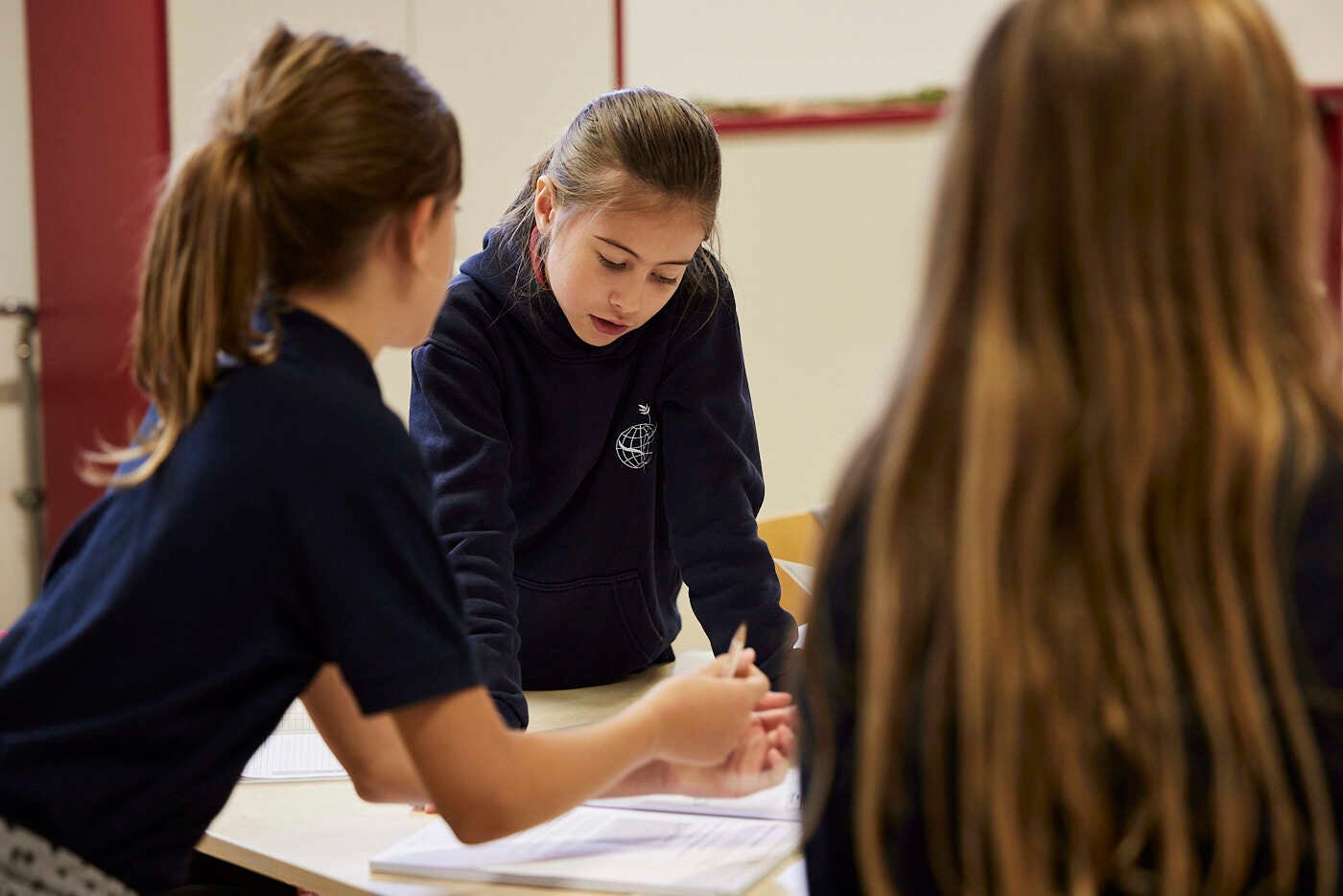 Drei junge Studentinnen diskutieren etwas in einer Klasse