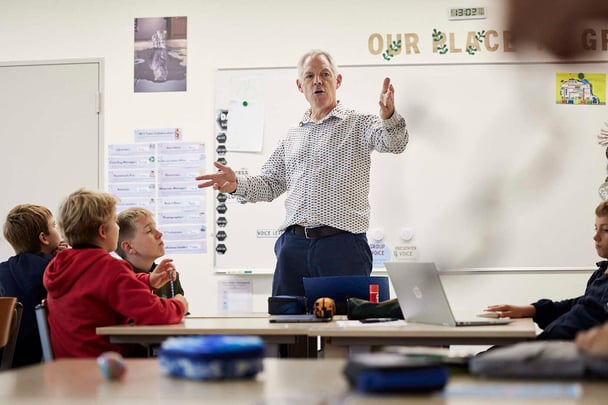 Ein Lehrer in Weiß spricht zu Schülern.
