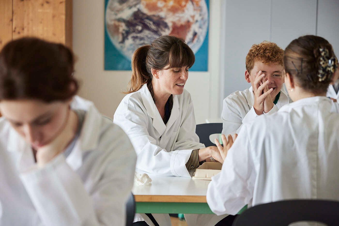 Eine Lehrerin und ihre anderen Schüler diskutieren in einem Labor