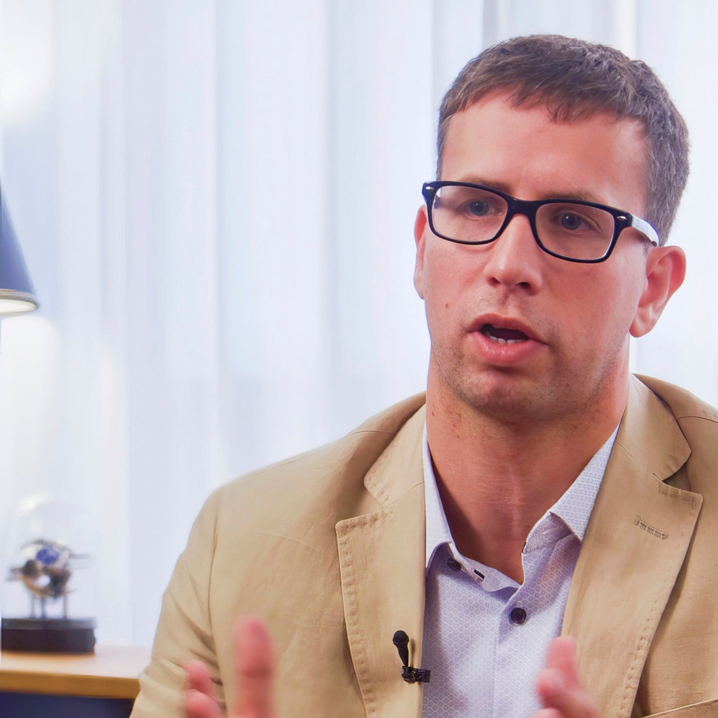 Ein Mann in gelbem Anzug und mit Brille.