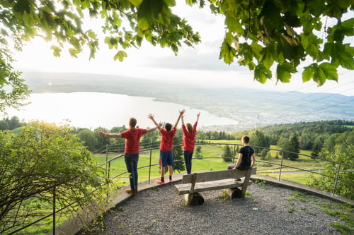 A group of people enjoy the view of Zug lake on a sunny day.