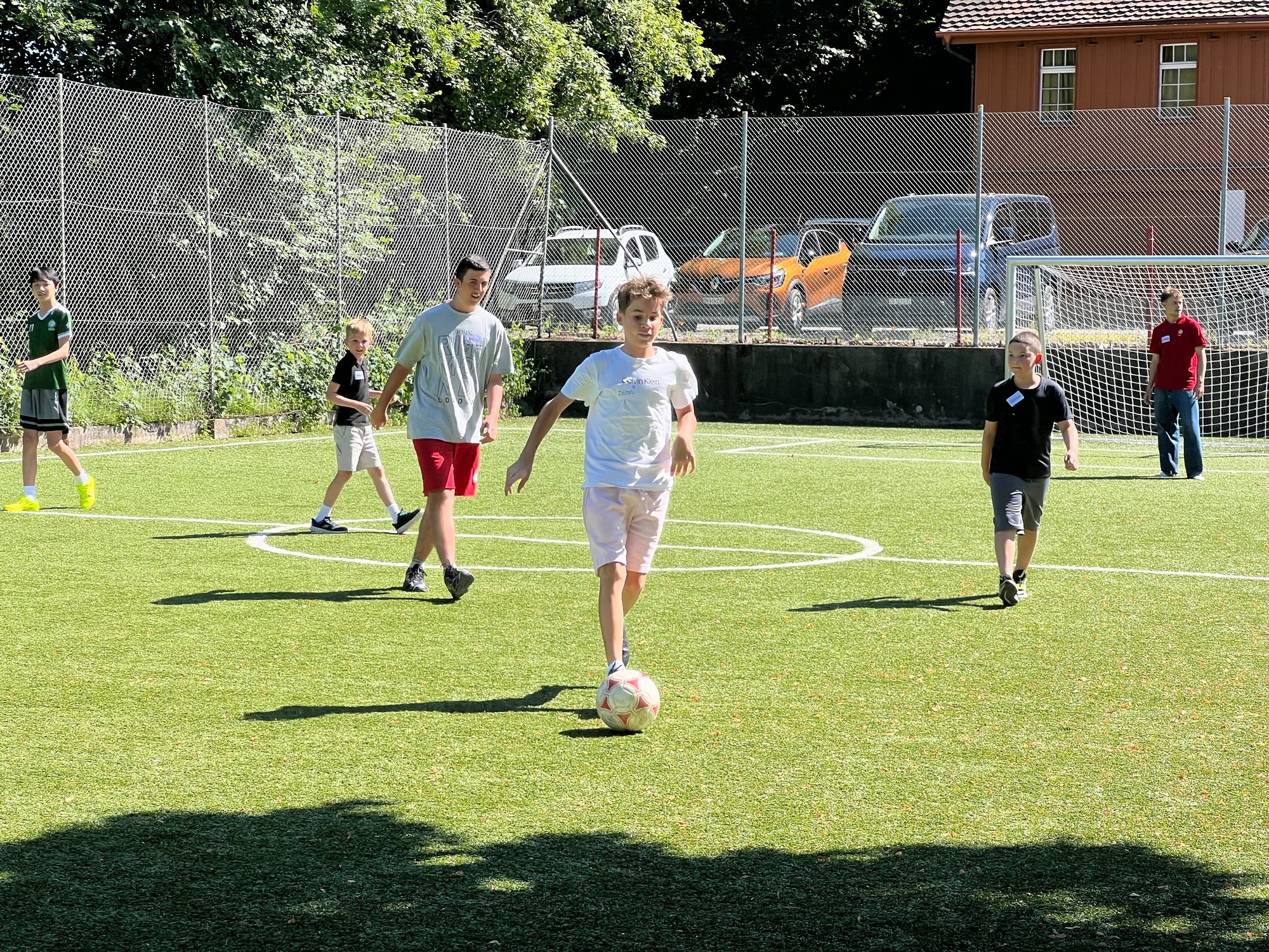 Einige Kinder spielen Fussball auf einem Feld.
