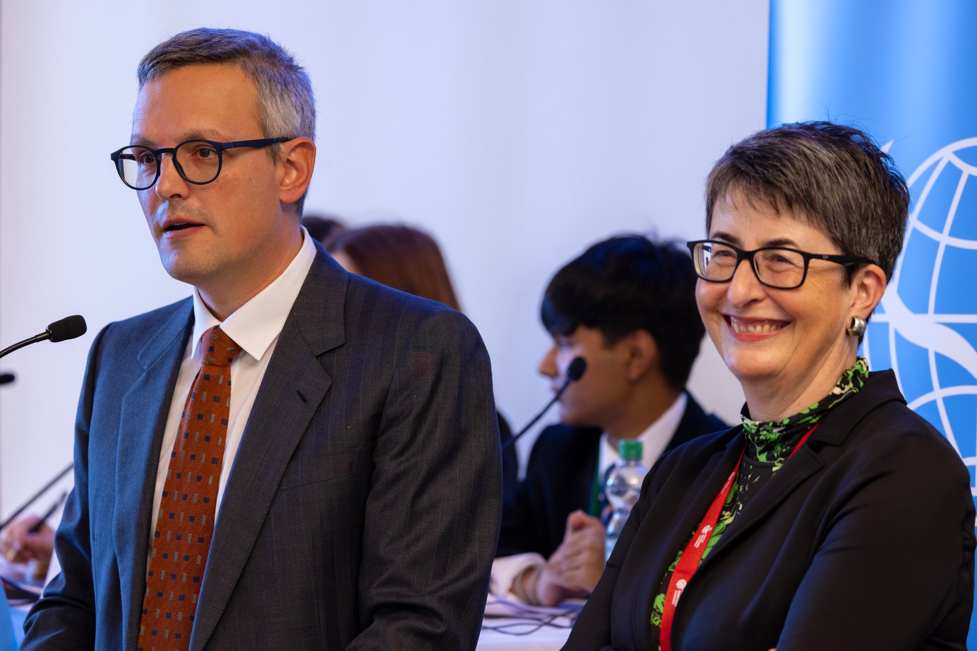 Ein Mann und eine Frau halten eine Rede auf einer Model United Nations-Konferenz.