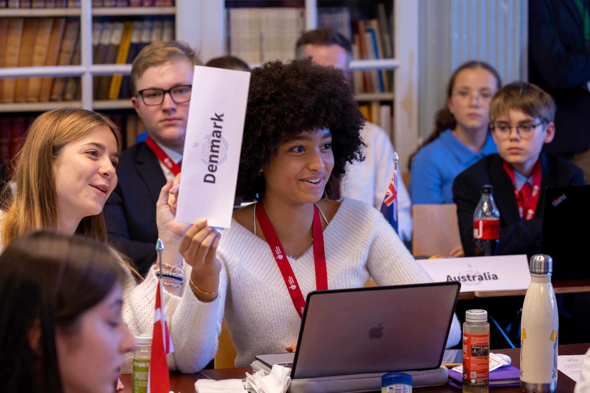 Eine Studentin, die an einer Konferenz teilnimmt, hebt ihr Schild, um zu sprechen.