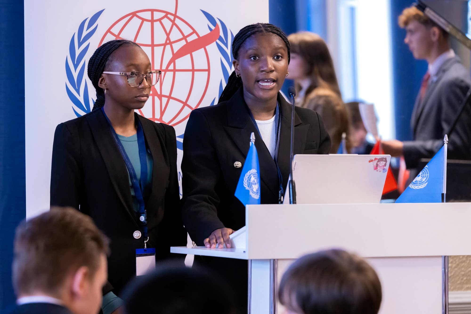 Zwei Studentinnen sprechen auf einem Podium der Model United Nations-Konferenz.