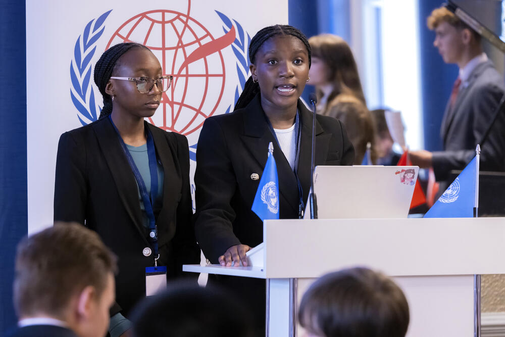 A couple of Zambian students talk at a podium.