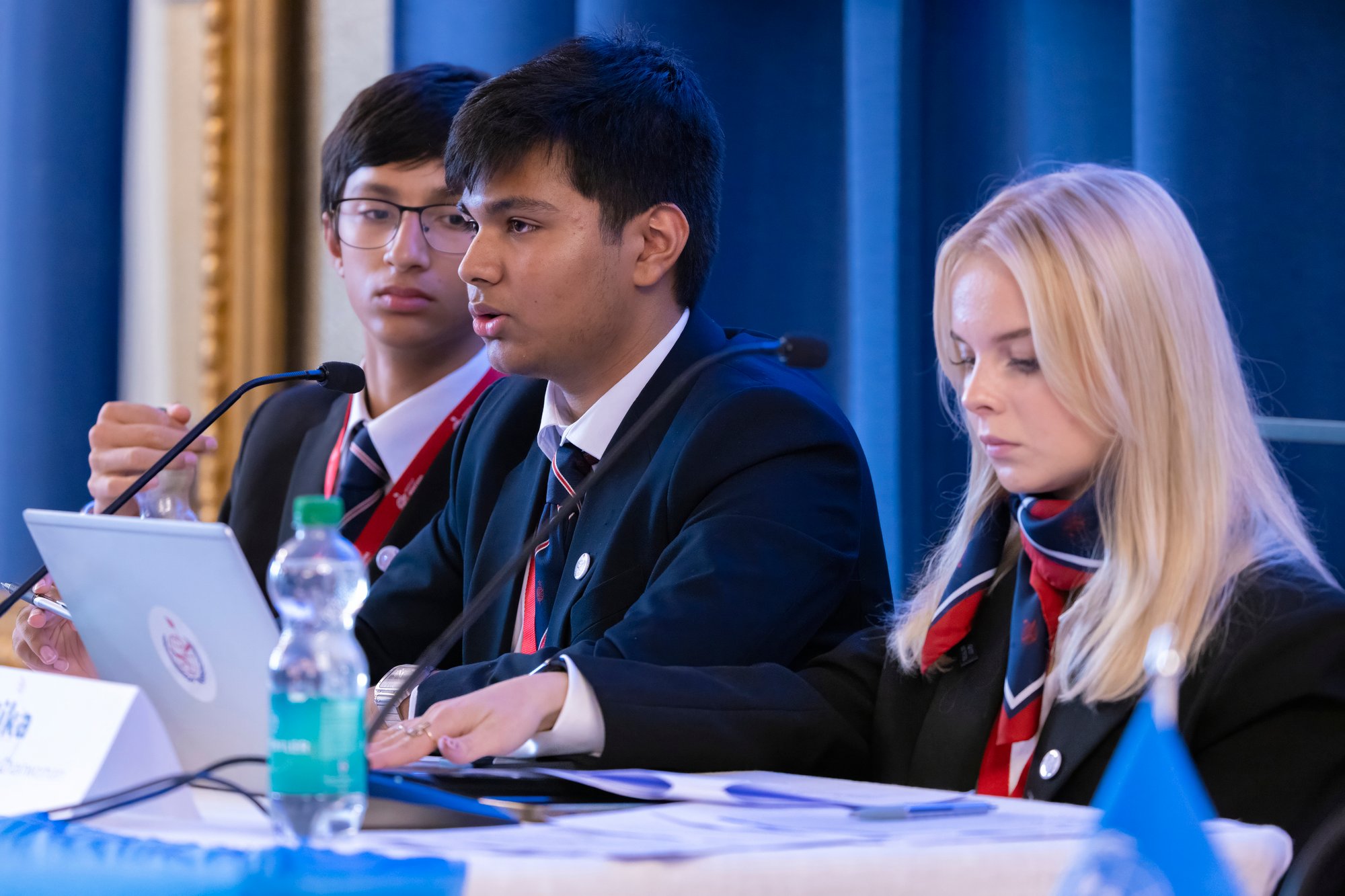 Zwei männliche und eine weibliche Studentin sitzen auf dem Stuhl der Model United Nations-Konferenz.