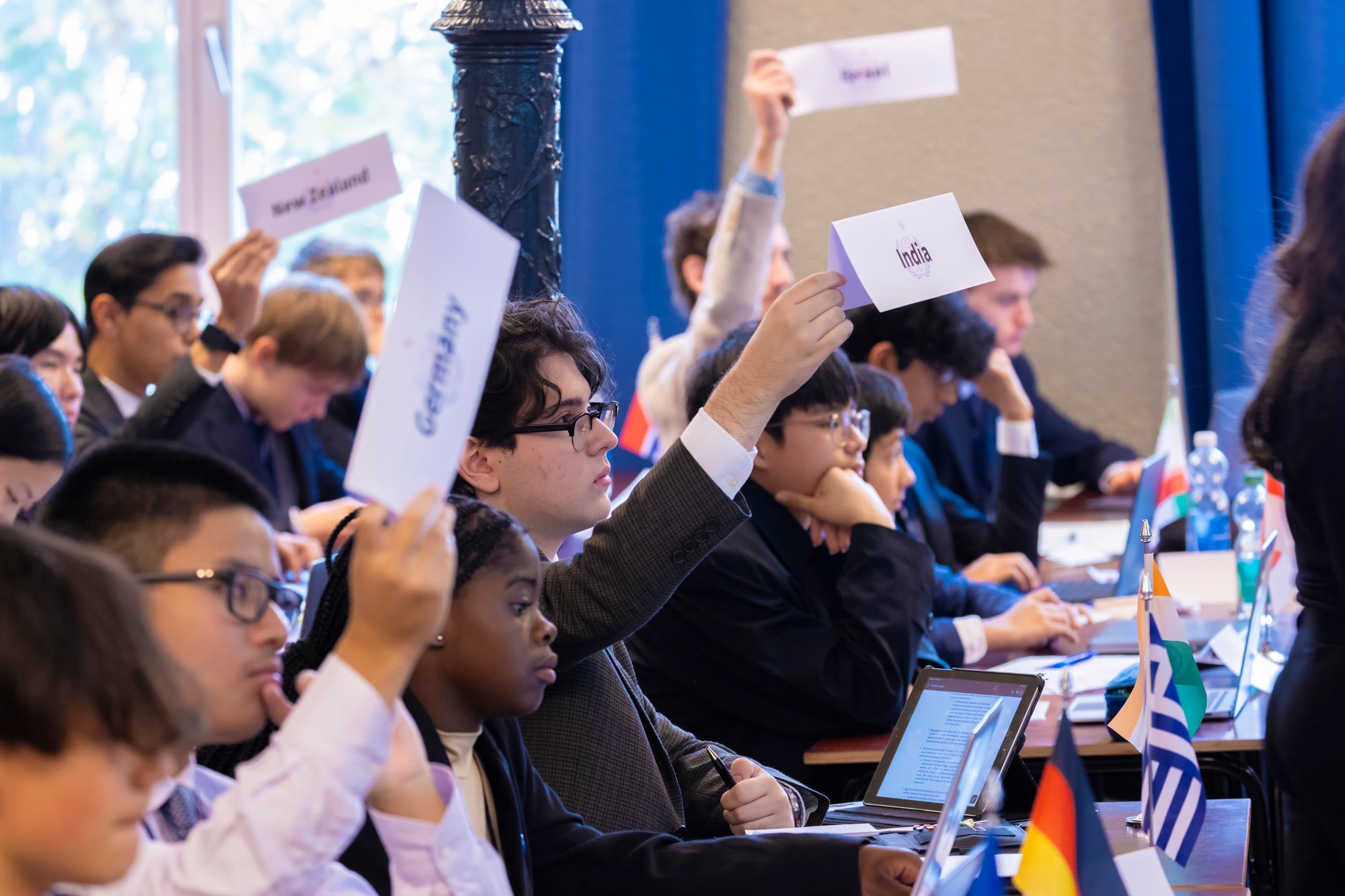 Eine Gruppe von Studenten hebt bei der Model United Nations Conference die Namensschilder ihrer Länderdelegationen.