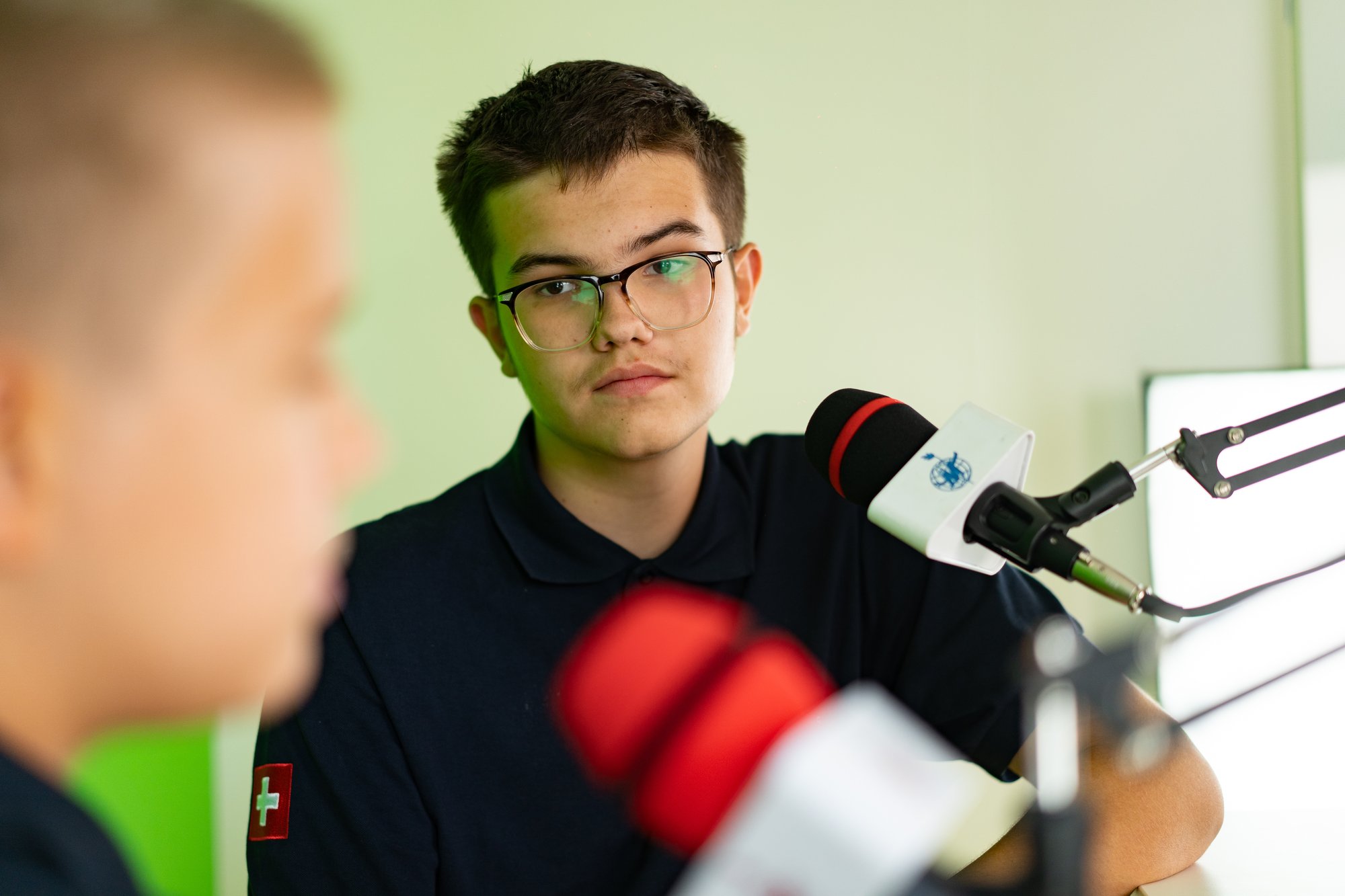 A boy student in a studio setting room interacts with another boy.
