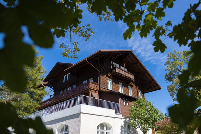 Ein klassisches Chalet-Gebäude aus Holz, umgeben von Bäumen.