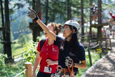 Two female students in an outdoor, one with the helmet is pointing at something.
