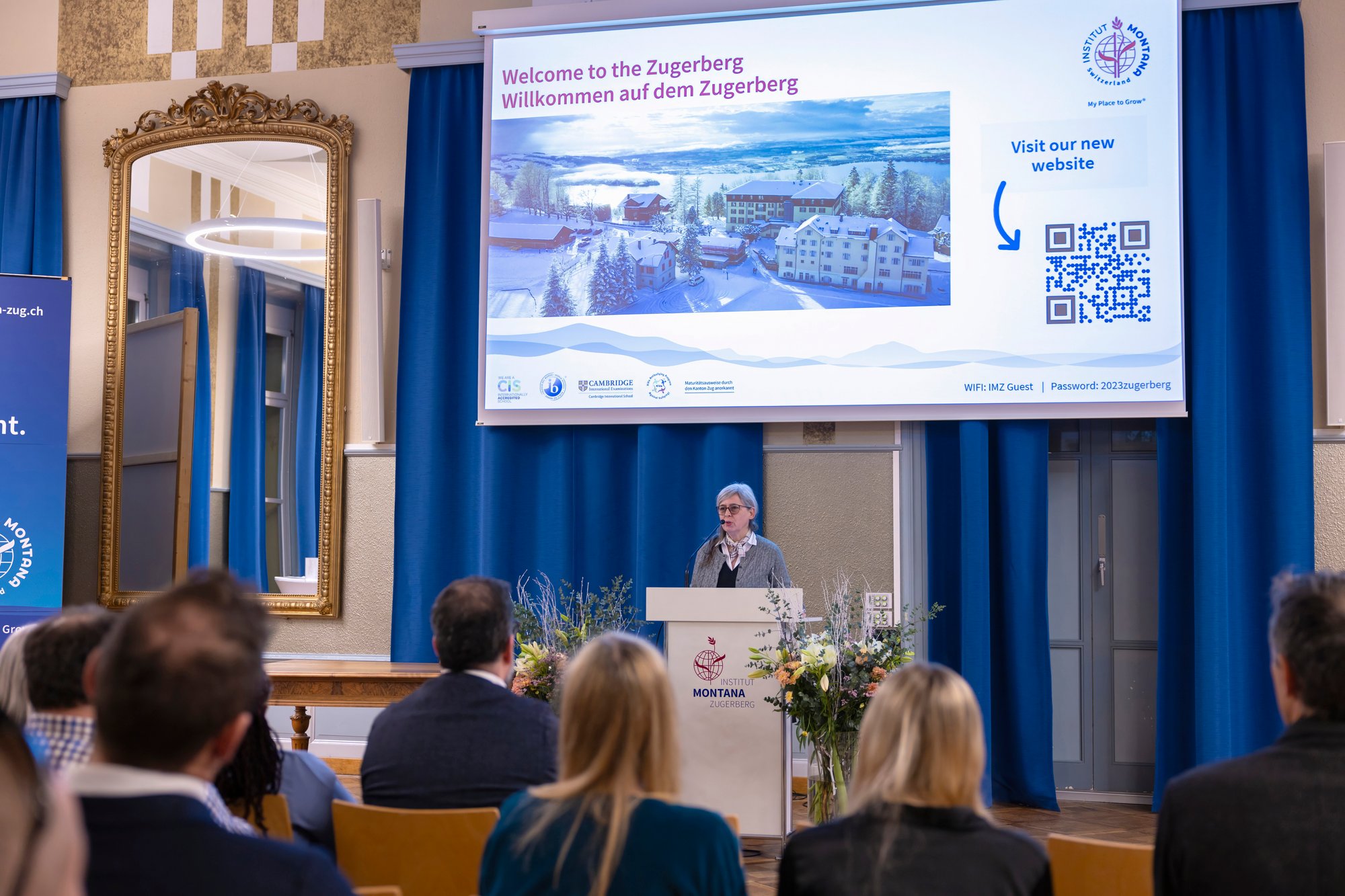 A lady gives a presentation in an aula to a group of people. A lady gives a presentation in an aula to a group of people.