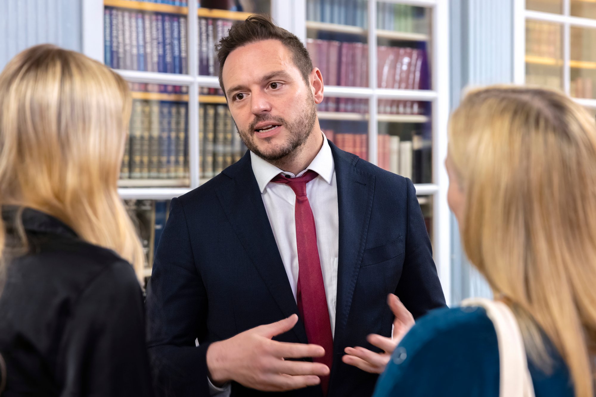 Ein Mann im Anzug spricht mit einer Mutter und einer Tochter.