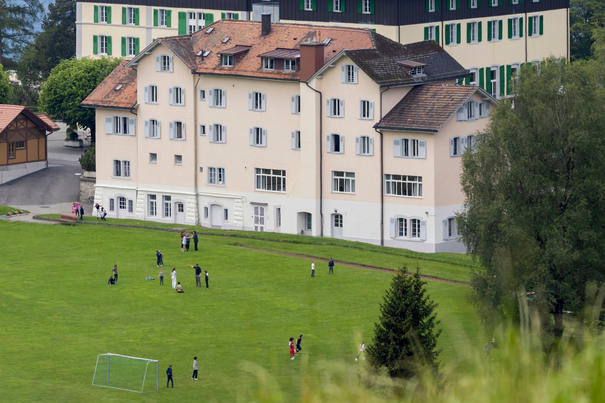 Ein hell gestrichenes Gebäude mit Kindern, die draußen Fußball spielen.