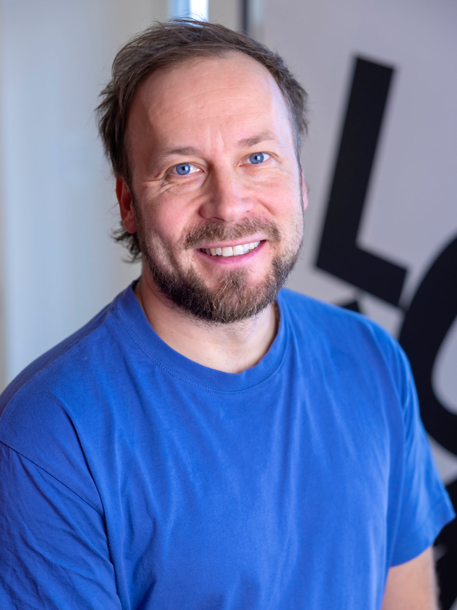 Portrait of a man wearing bright blue top. 