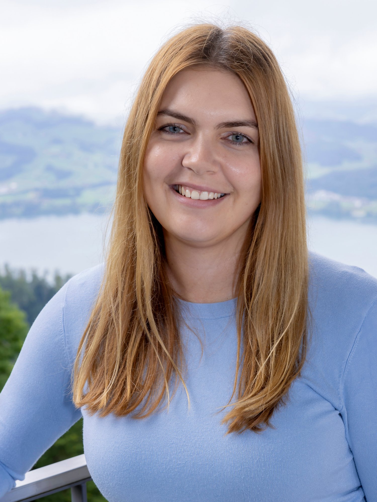 Portrait of a blond long-haired woman wearing blue top.
