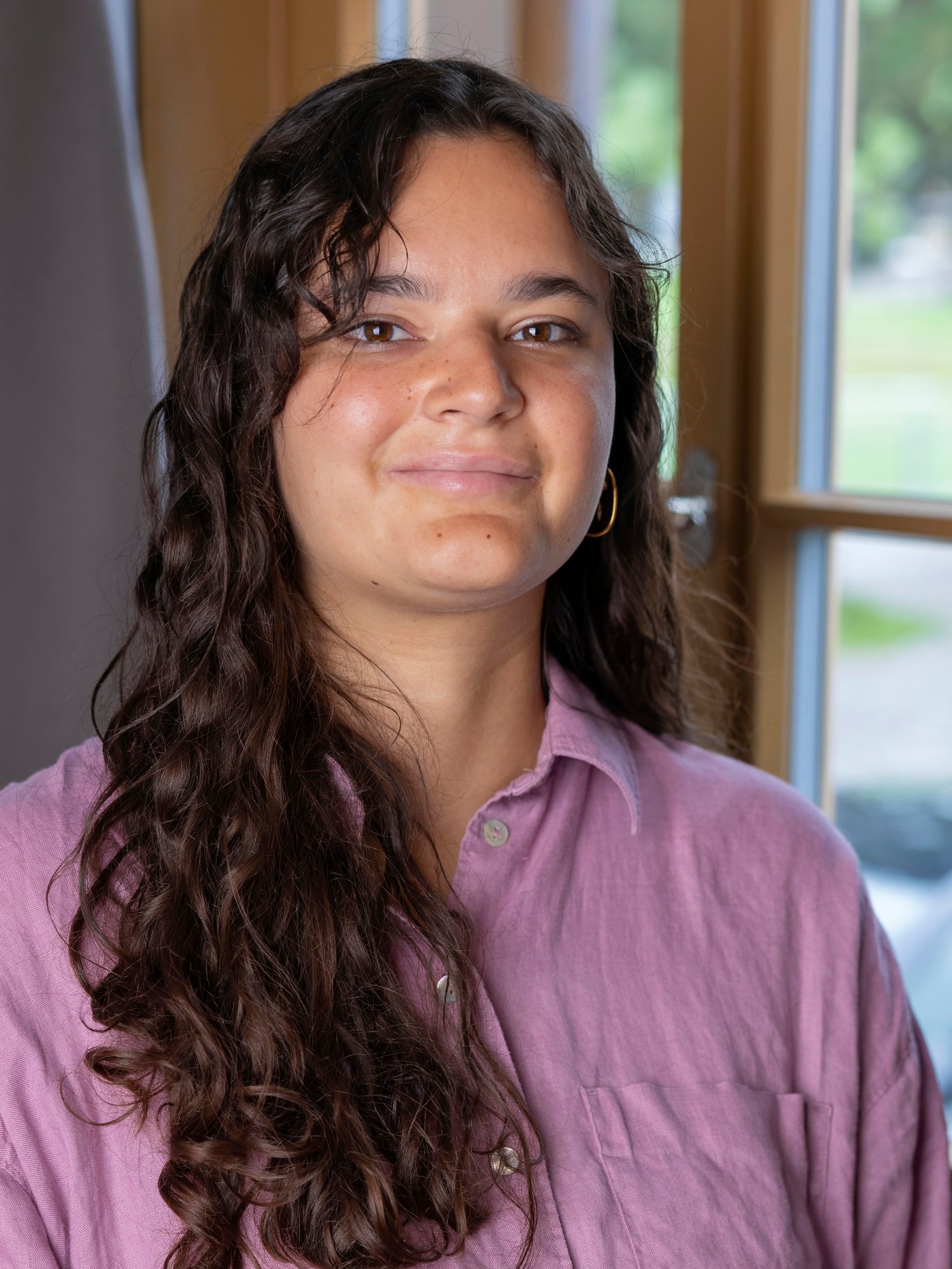 A female staff with long hair smiling to the camera..